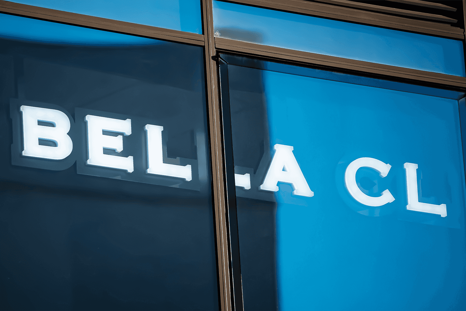 Letras LED luminosas "BELLA CLINICA" en una fachada de cristal