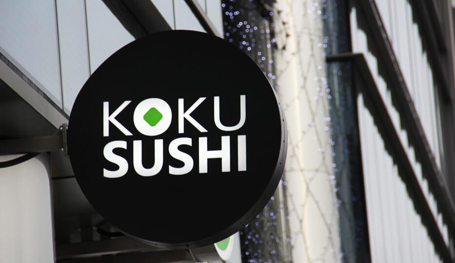 Koku Sushi - runder Leuchtkasten mit Werbung neben dem Eingang