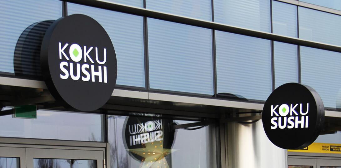 Koku Sushi - runder Leuchtkasten mit Werbung neben dem Eingang