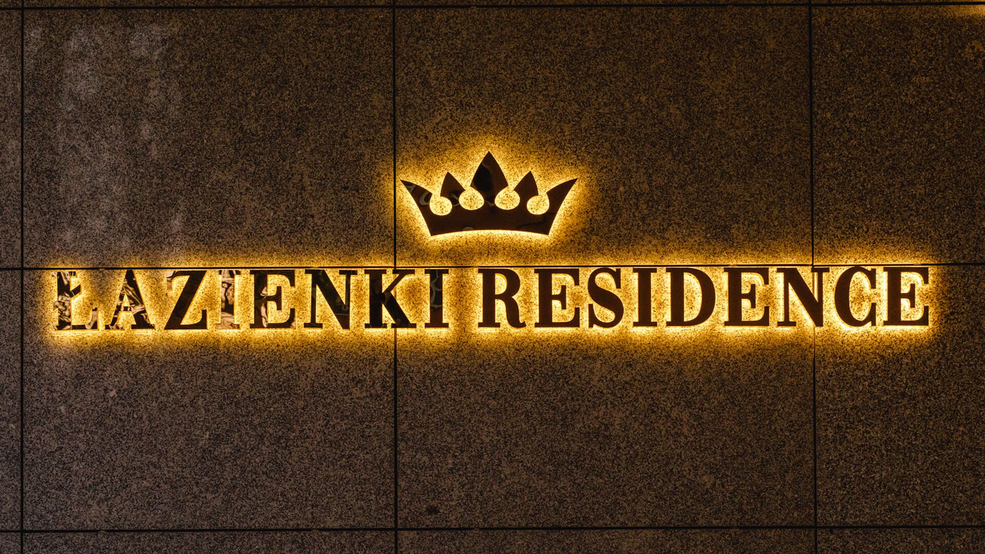 Łazienki Residence - Napis Łazienki Residence wykonany z blachy nierdzewnej w kolorze złotym, podświetlane LED tyłem na ściane, z koroną w logo.