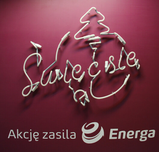 Shine up - Energa - white neon advertising sign with symbols placed on the wall