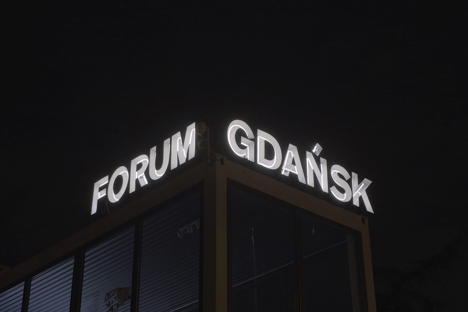 Forum Gdansk - lettres lumineuses au néon, montées sur un cadre, placées sur le toit du bâtiment.