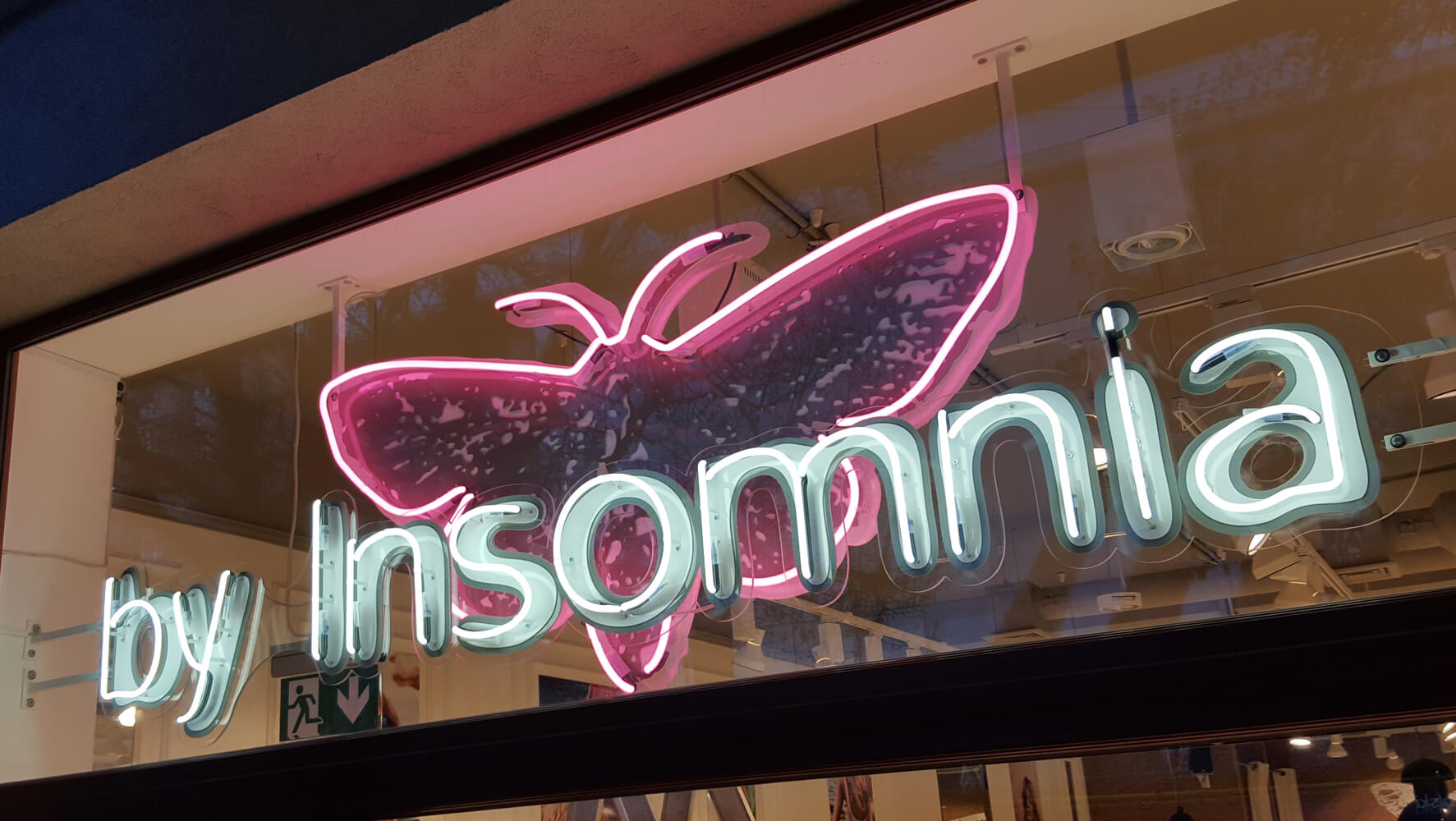 By Insomnia - neon sign with the company's name, mounted on plexiglass, placed behind the glass window