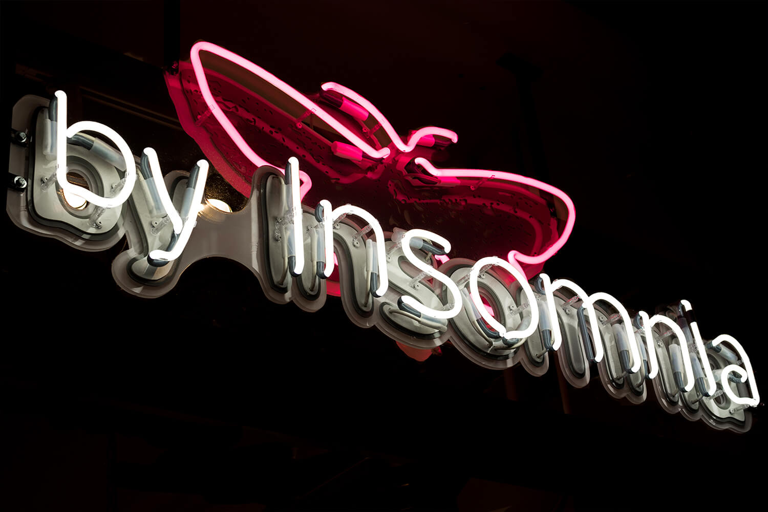 By Insomnia - insegna al neon con il nome dell'azienda, montata su plexiglas, posizionata dietro la vetrata