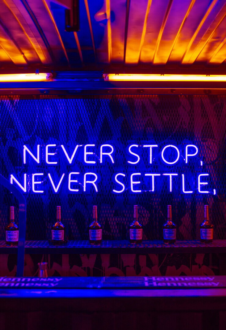 never-stop-never-settle-hennessy-neon-advertising-hennessy-neon-lettering-neon-inscription-on-the-counter-bottle-blue-neon-behind-the-bar