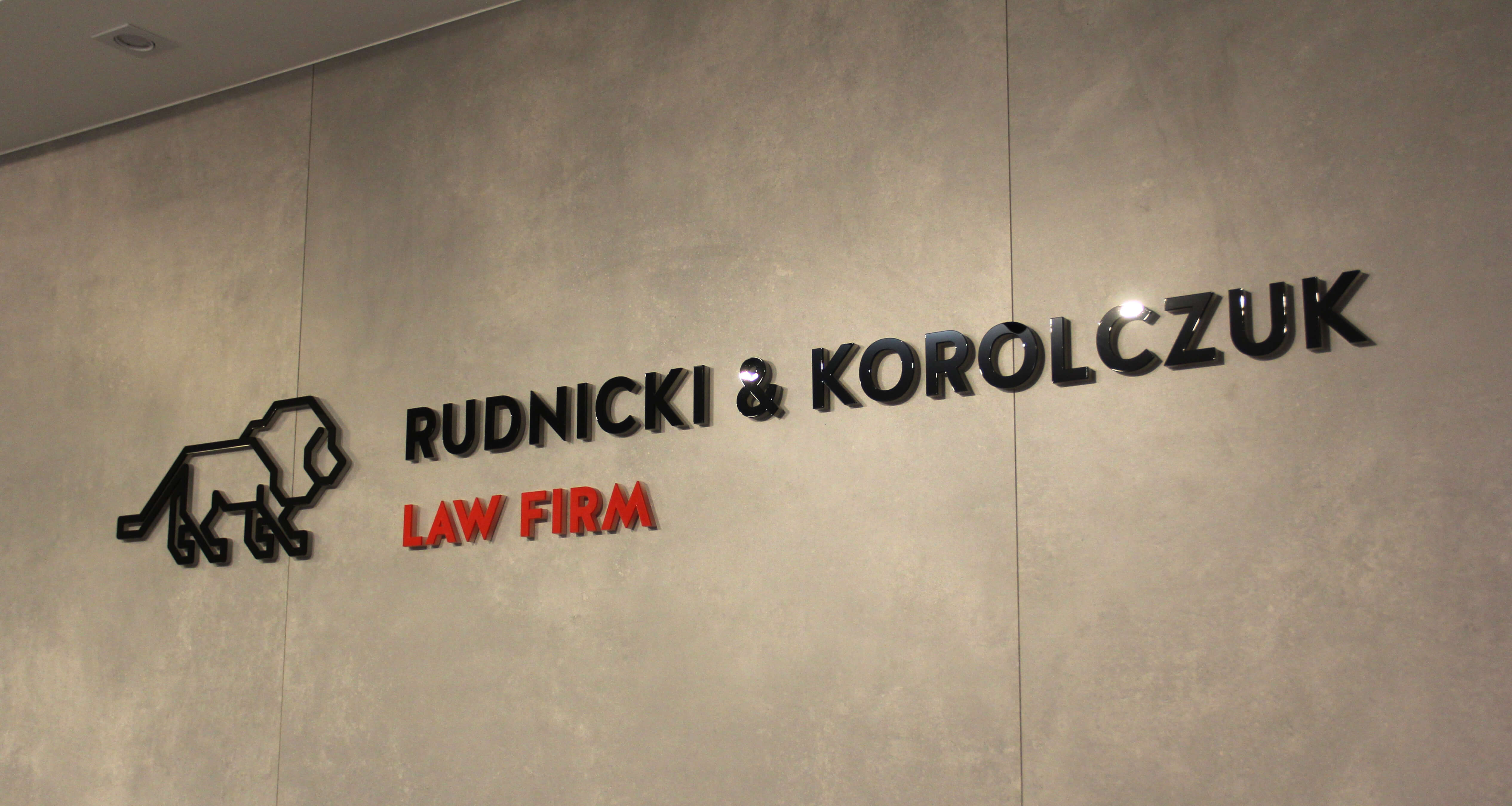 Rudnicki i Korolczuk - 3D-Logo und Buchstaben aus Plexiglas an der Wand im Inneren des Gebäudes