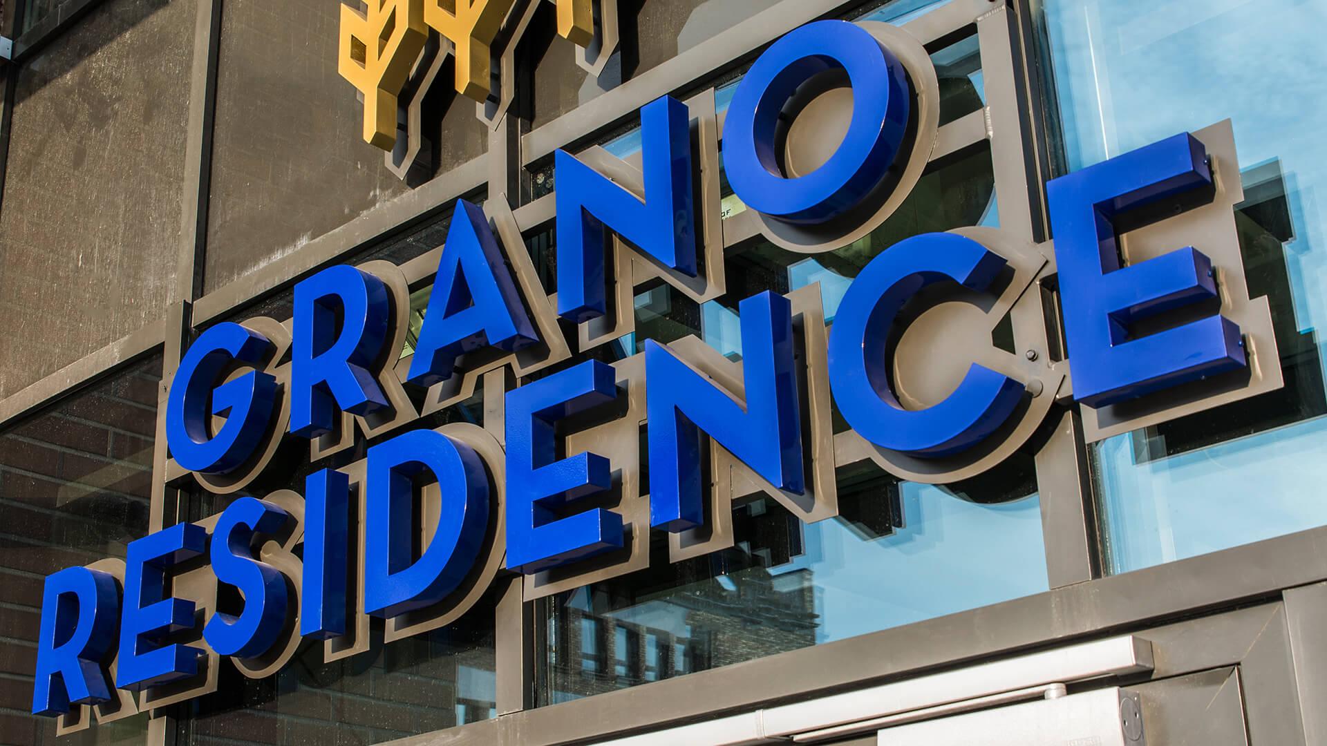 grano-residence-literature-space-lit-back-lit-blue-literature-above-entry-to-hotel-literature-mounted-on-capital-literature-on-stack-logo-firm-3d-gdansk