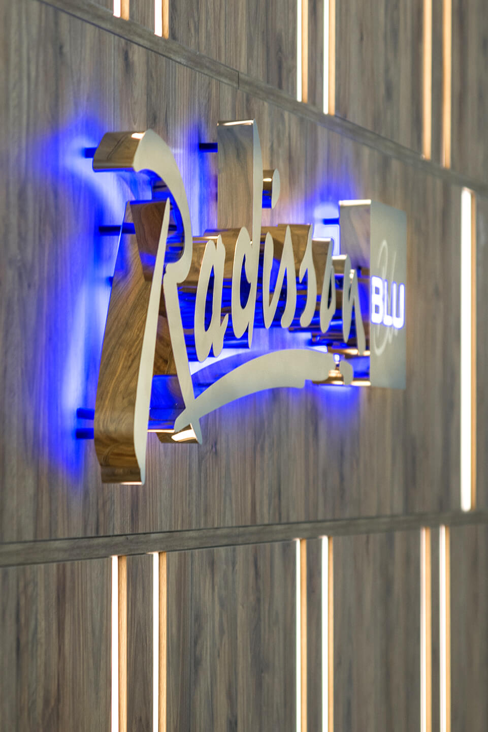 radisson-blu-lettere-dalla-placca-argento-lettere-d'oro-reception-in-hotel-su-una-parete-di-legno-lettere-illuminate-dal-blu-sopot-logo-compagnia-esclusiva-glamour