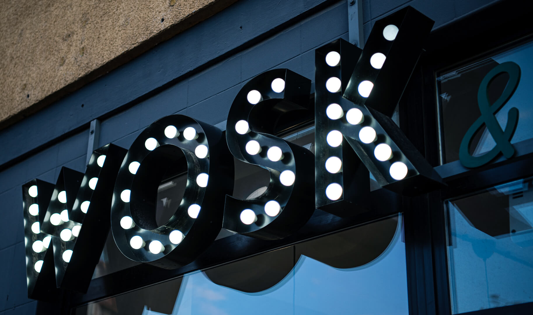 Letters with bulbs forming the word WOSK, white bulbs embedded in black letters