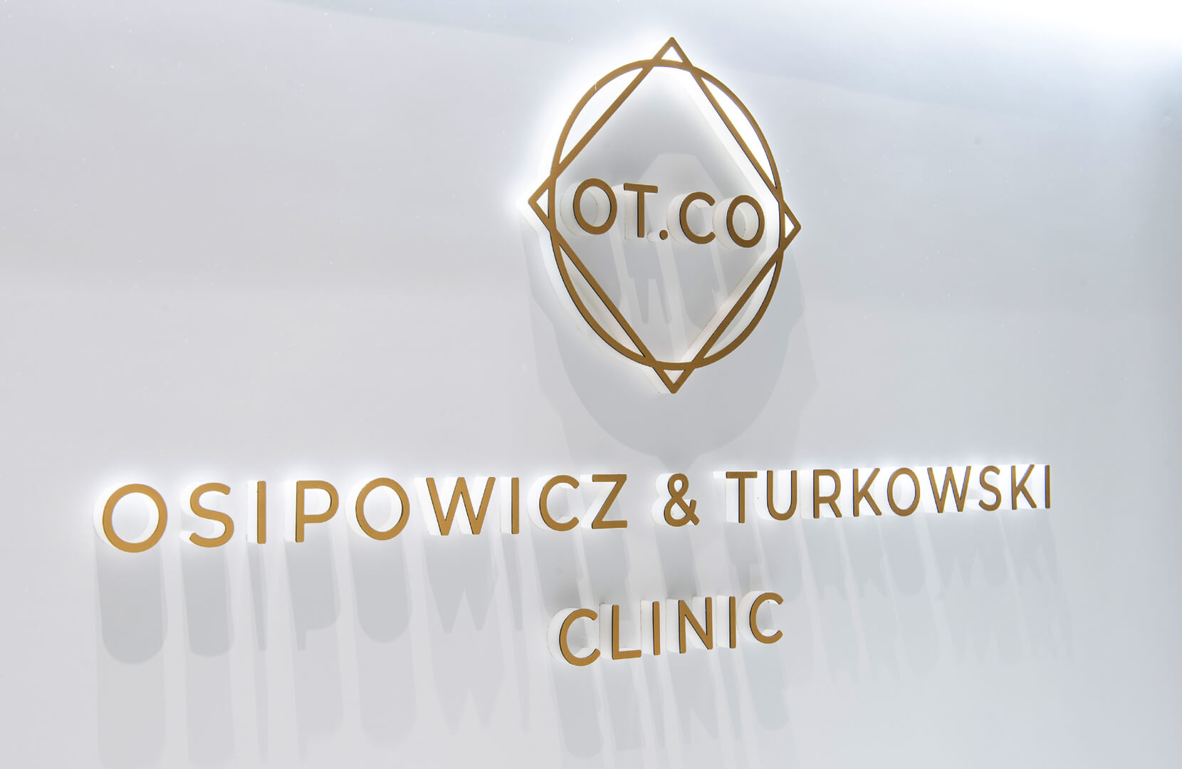 Letras espaciales doradas con logotipo en la recepción de la clínica OT.CO