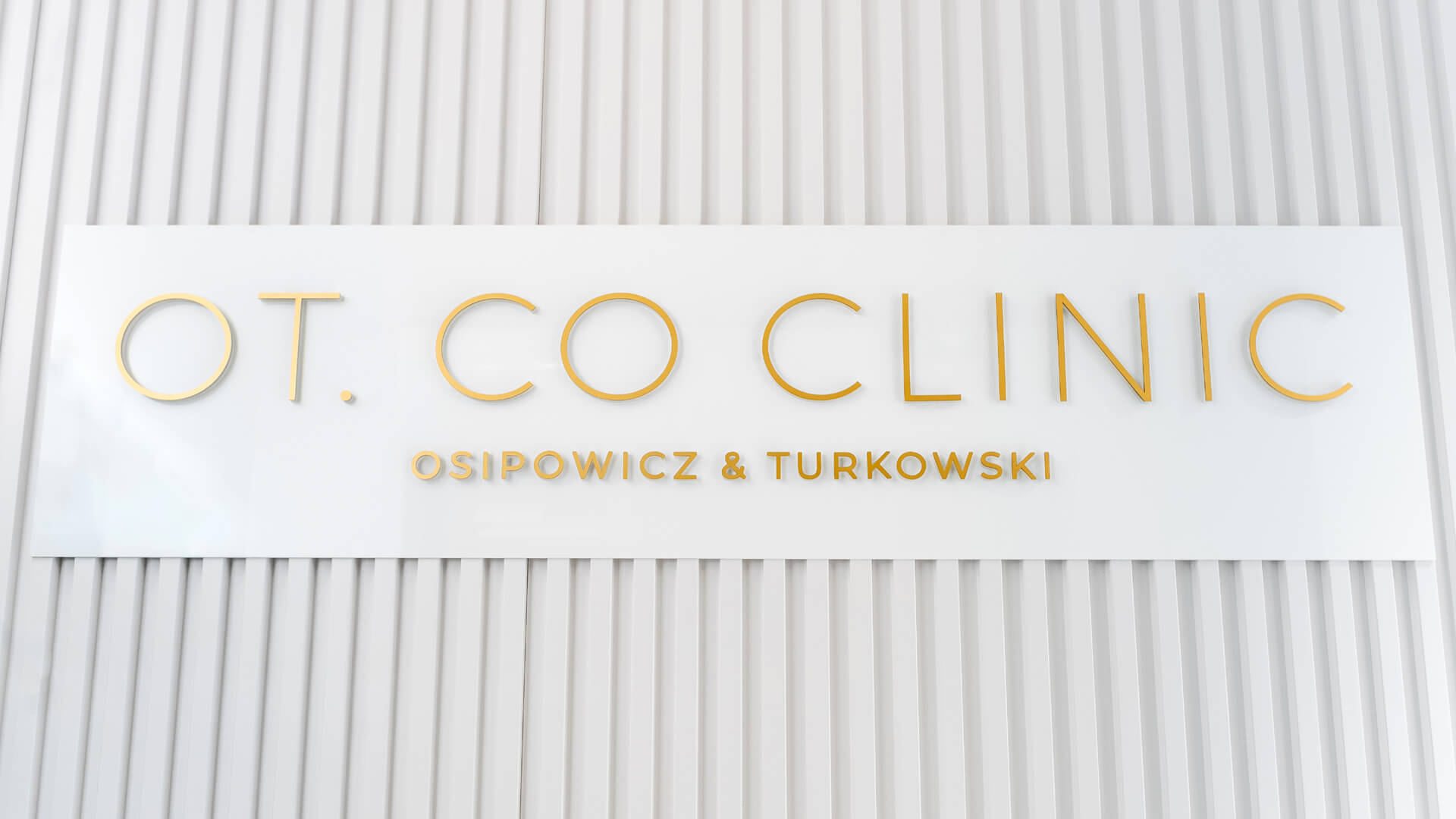 Złote litery pryzmatyczne na ścianie w recepcji OT.CO Clinic