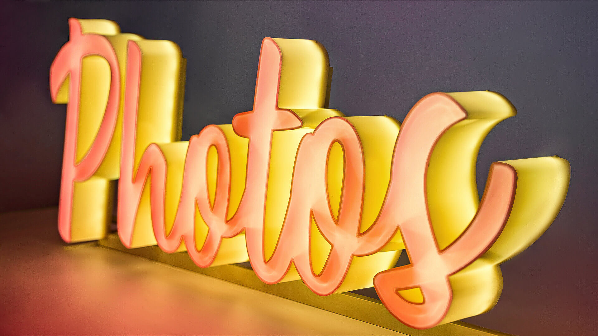 Letras de plexiglás brillantes en la parte frontal y lateral, de color naranja.