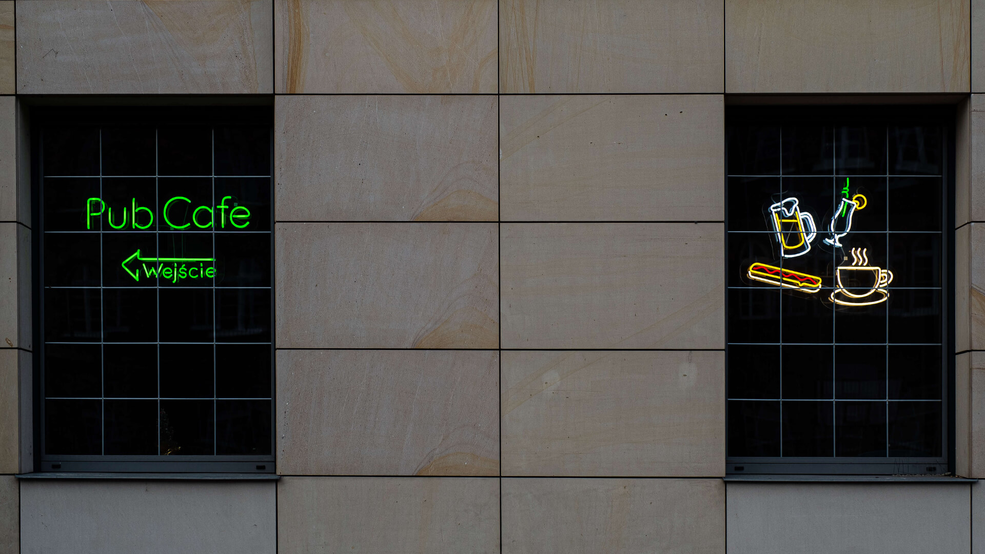 Green neon Pub Cafe sign with directions to the entrance.