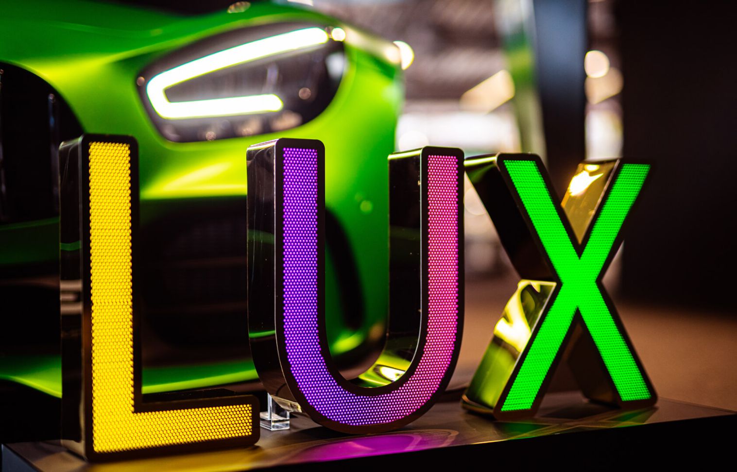 LUX inscription made of perforated stainless steel sheet, illuminated with LED in three colors, on the background of Mercedes