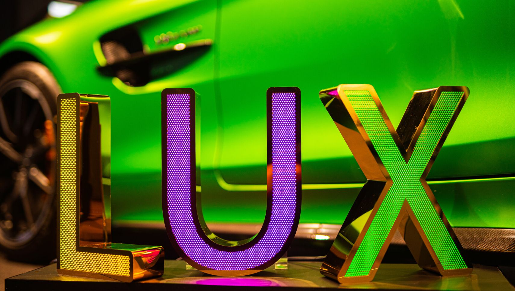 LUX inscription made of perforated stainless steel sheet, illuminated with LED in three colors, on the background of Mercedes