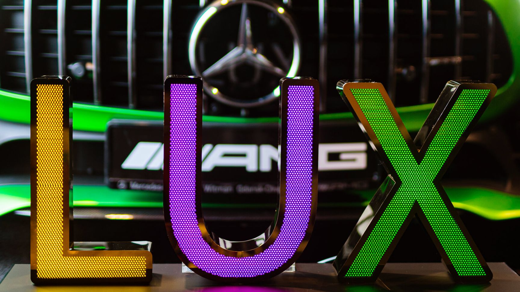 LUX inscription made of perforated stainless steel sheet, illuminated with LED in three colors, on the background of Mercedes