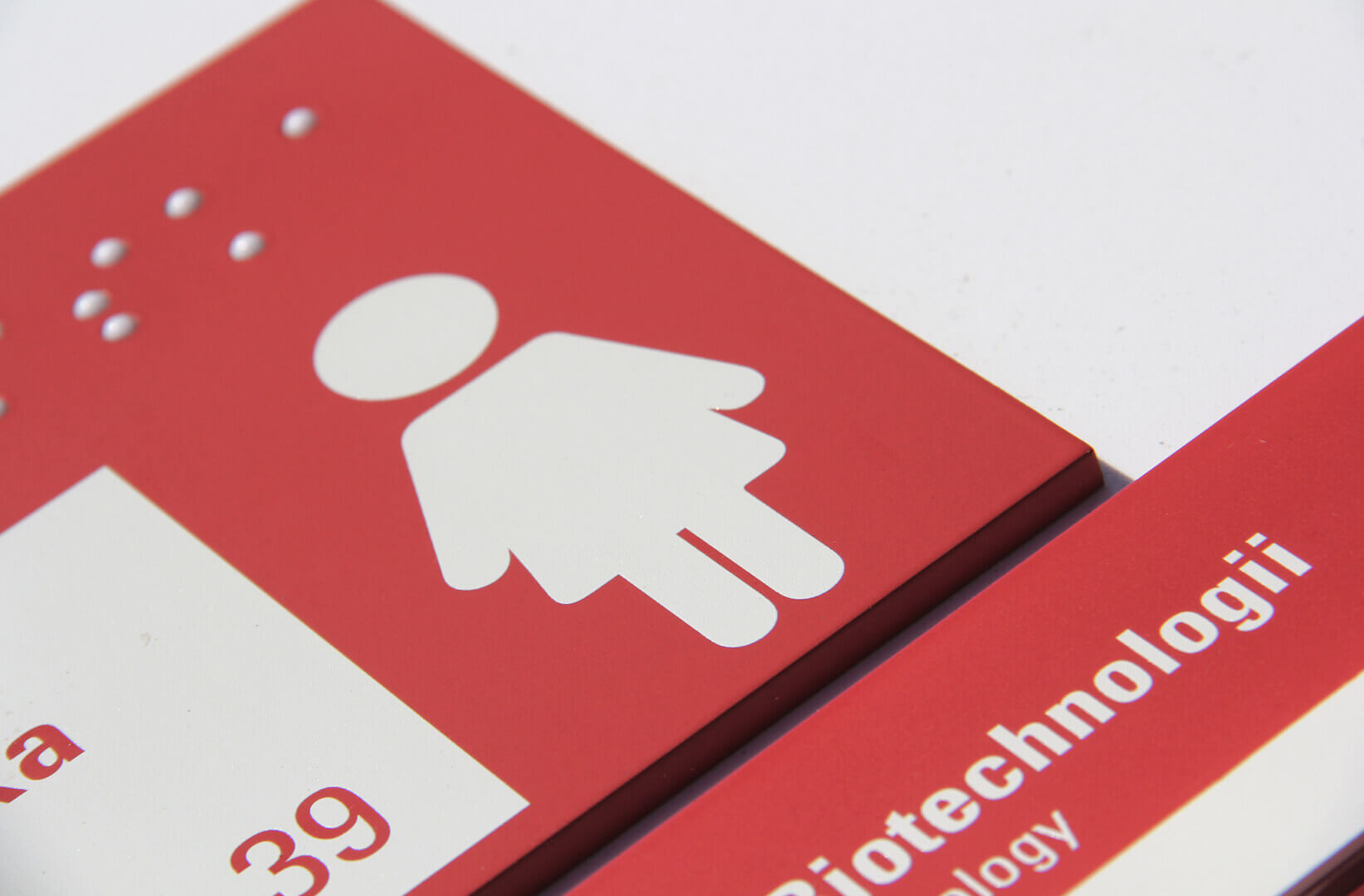 Braille plaque, university signage, in white and red.