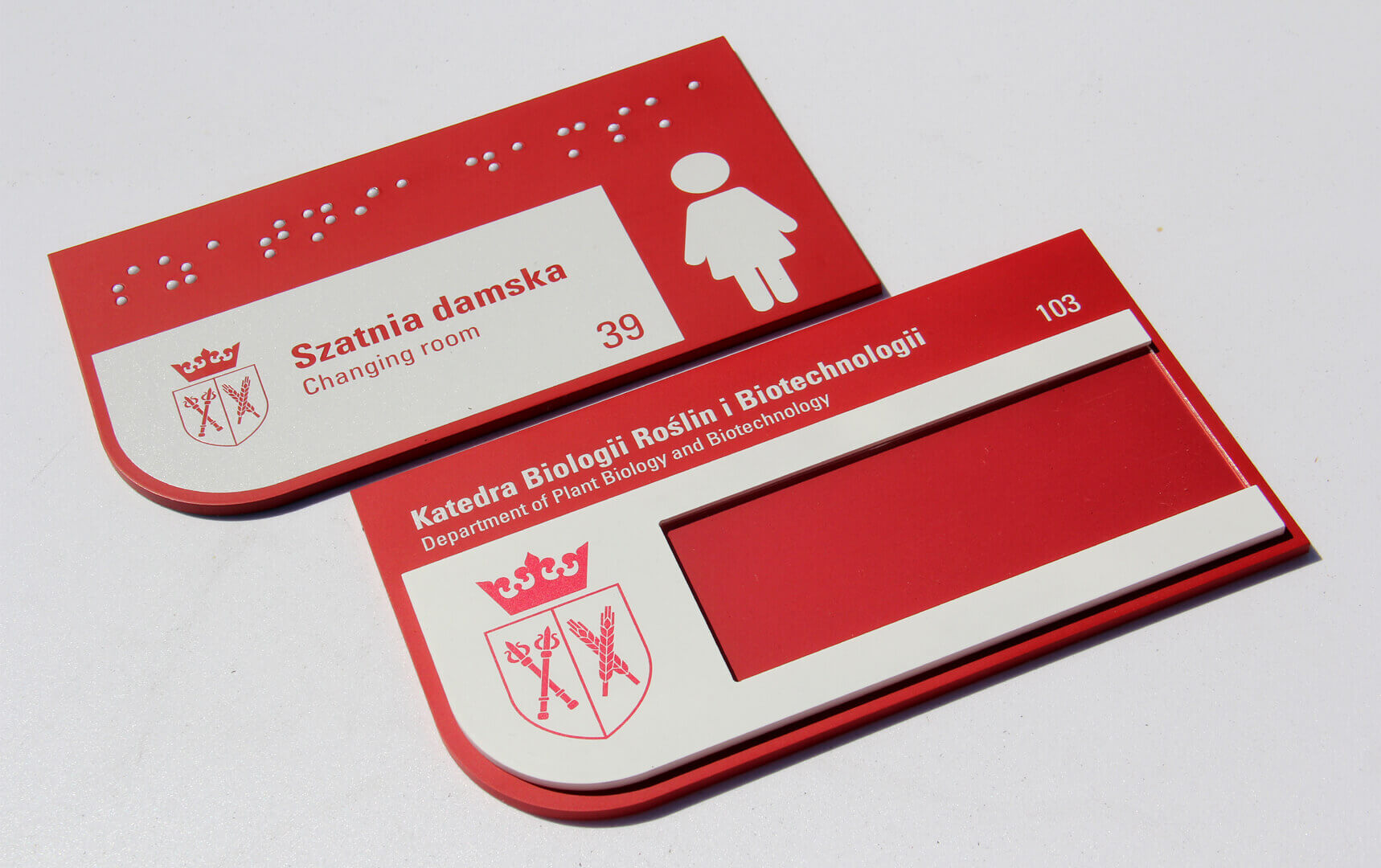 Signalisation en braille des vestiaires féminins, en rouge et blanc.