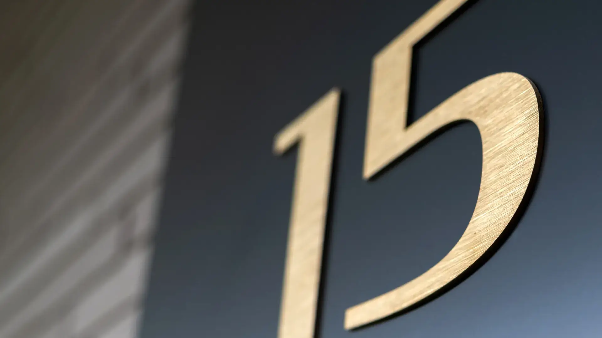 Numeral 15 in gold brushed polished sheet metal.