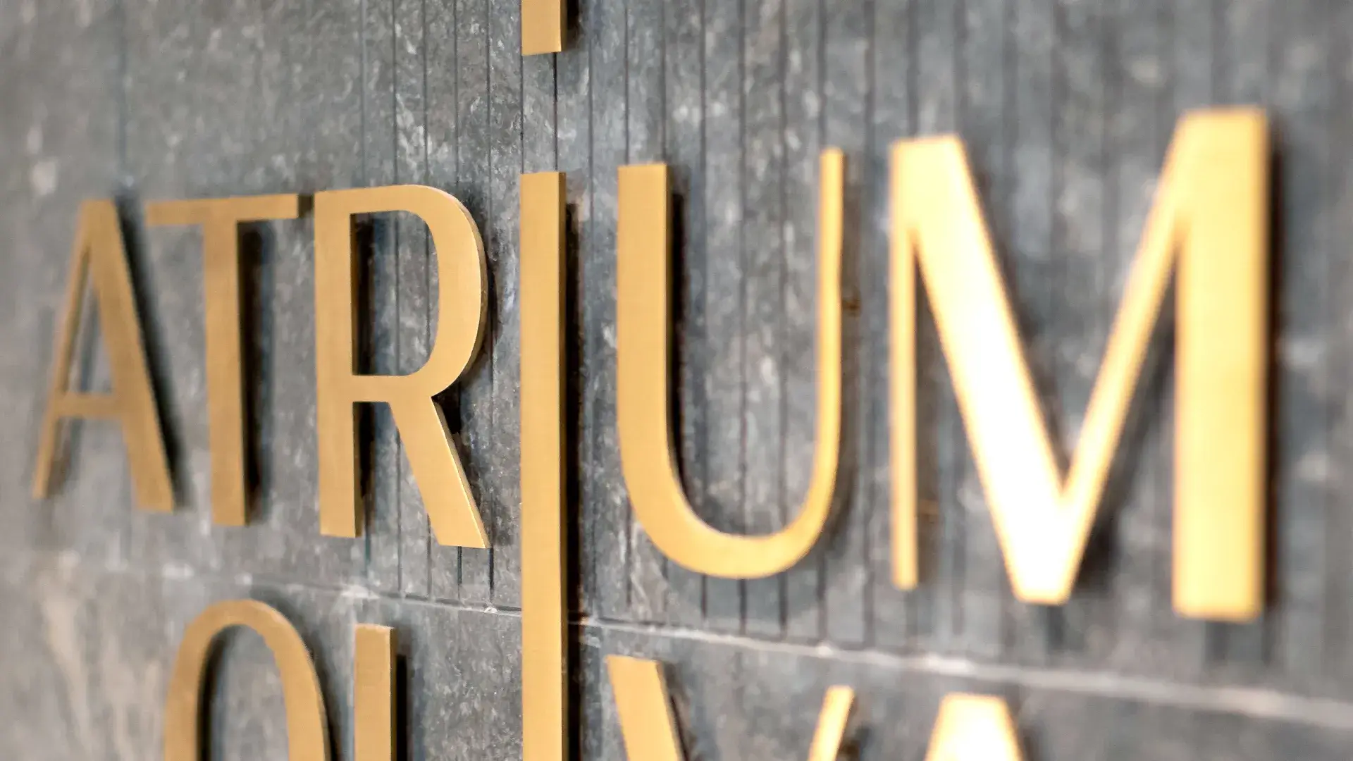 Atrium Oliva's gold flat letters in brushed sheet metal