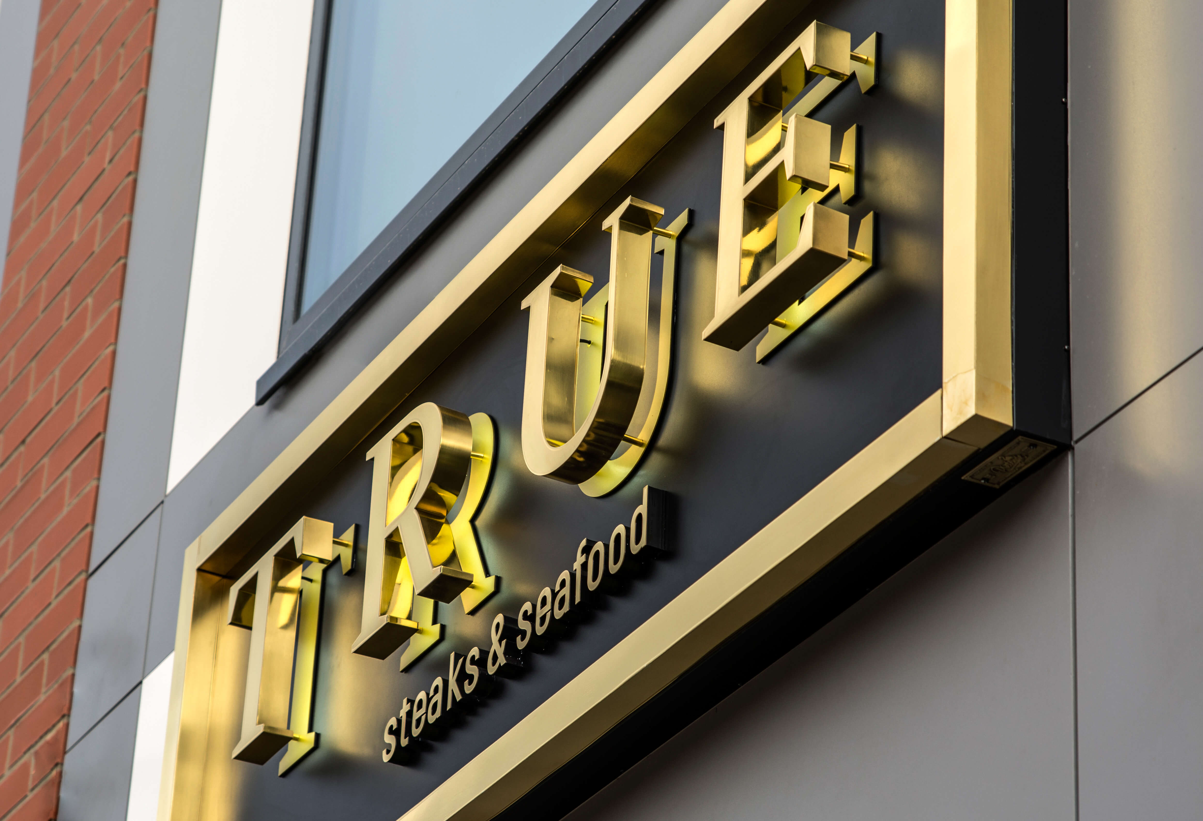 True - outdoor signboard with golden spatial letters made of stainless steel sheet