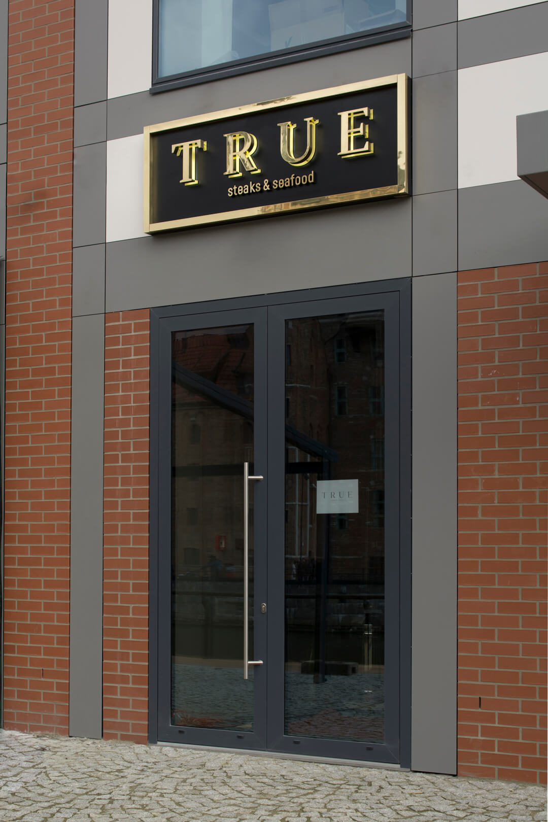 True - outdoor signboard with golden spatial letters made of stainless steel sheet