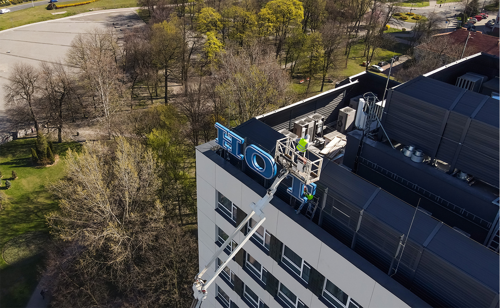 Montaż neonu Hotel Katowice przy użyciu dźwigu na dachu budynku