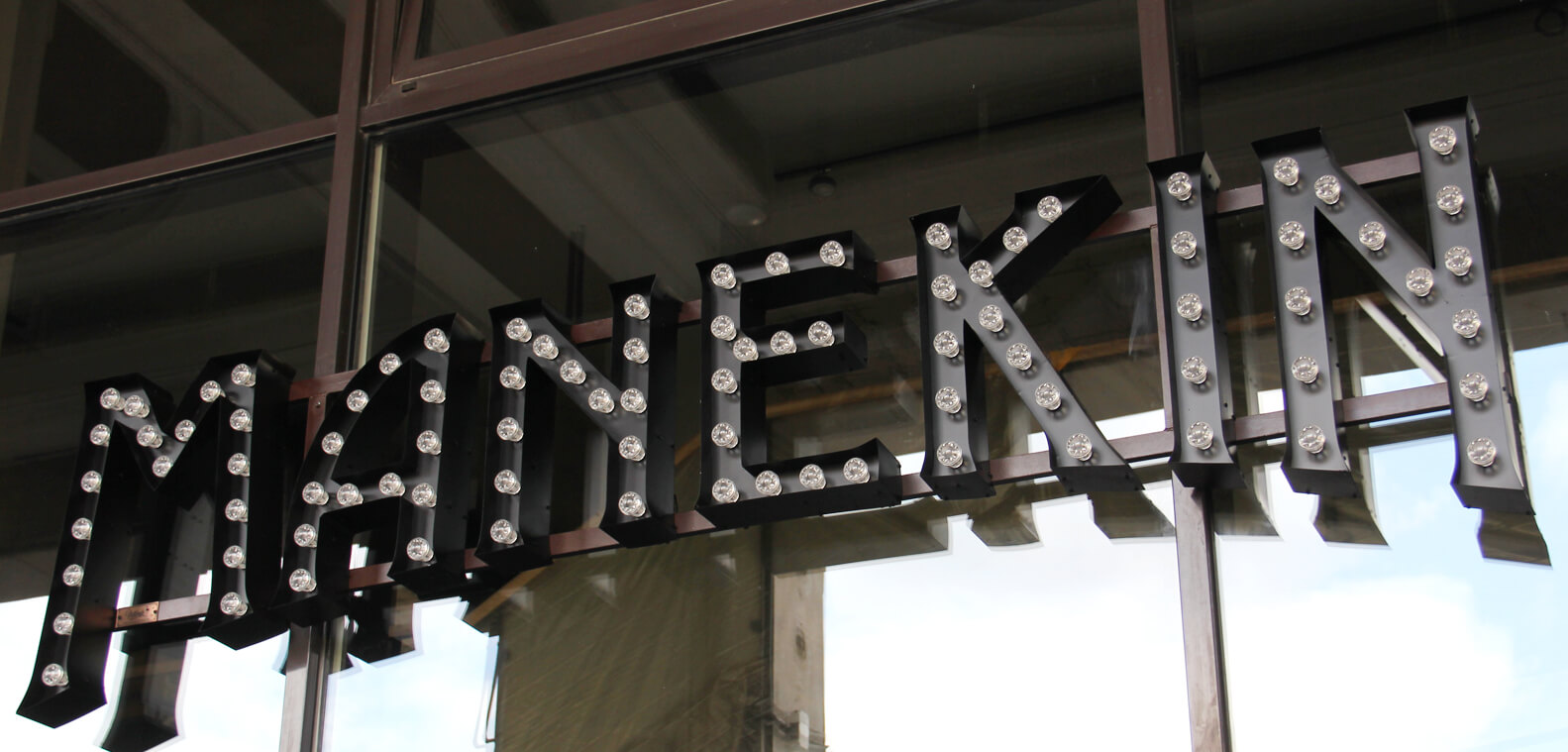 Mannequin - Letters with bulbs placed on a rack above the entrance