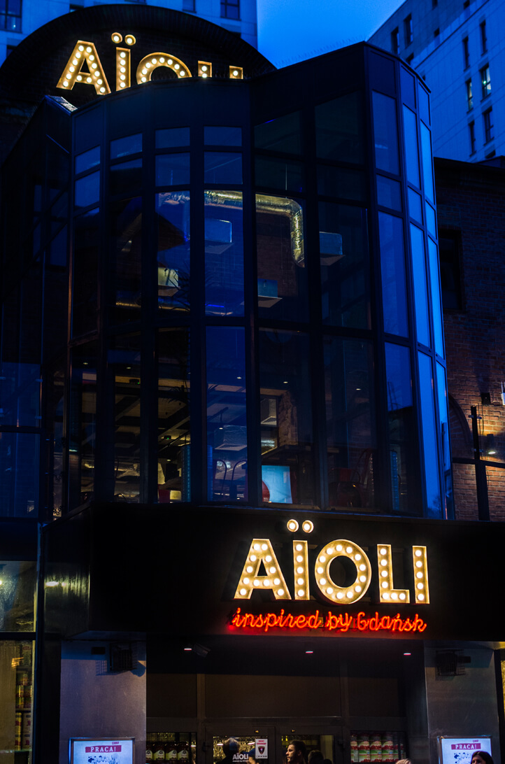 Aioli - company signboard composed of letters with bulbs above the entrance