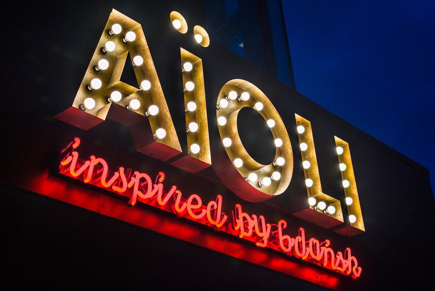 Aioli - company sign composed of letters with bulbs above the entrance