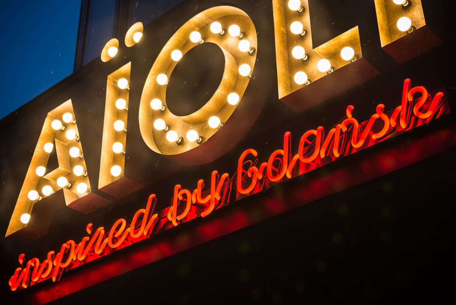 Aioli - company sign composed of letters with bulbs above the entrance