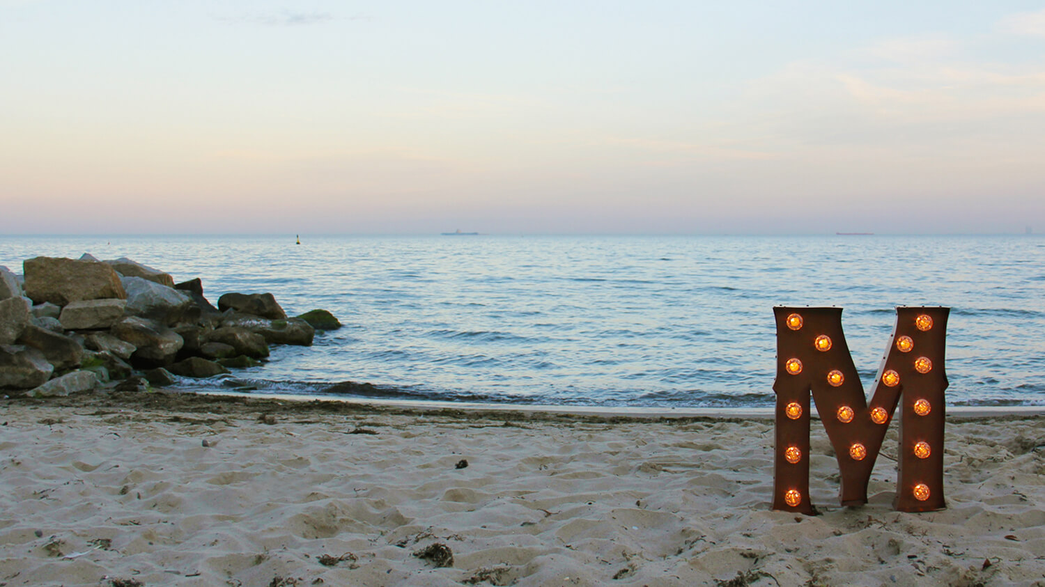 Spatial standing lettering with light bulbs on a beach