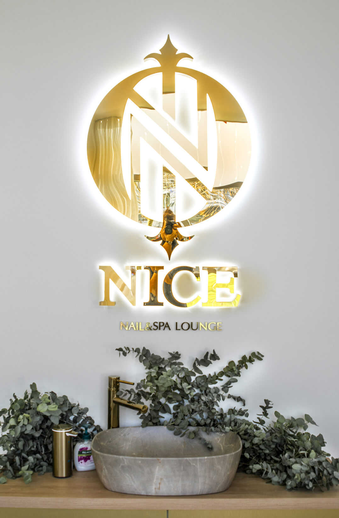 NICE - Hübsch - goldenes Logo und Buchstaben im Querformat an der Rezeption