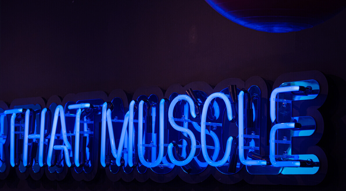 Hustle for that muscle - blue neon sign on the wall