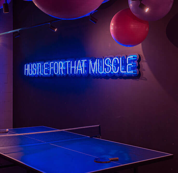 Hustle for that muscle - blue neon sign on the wall