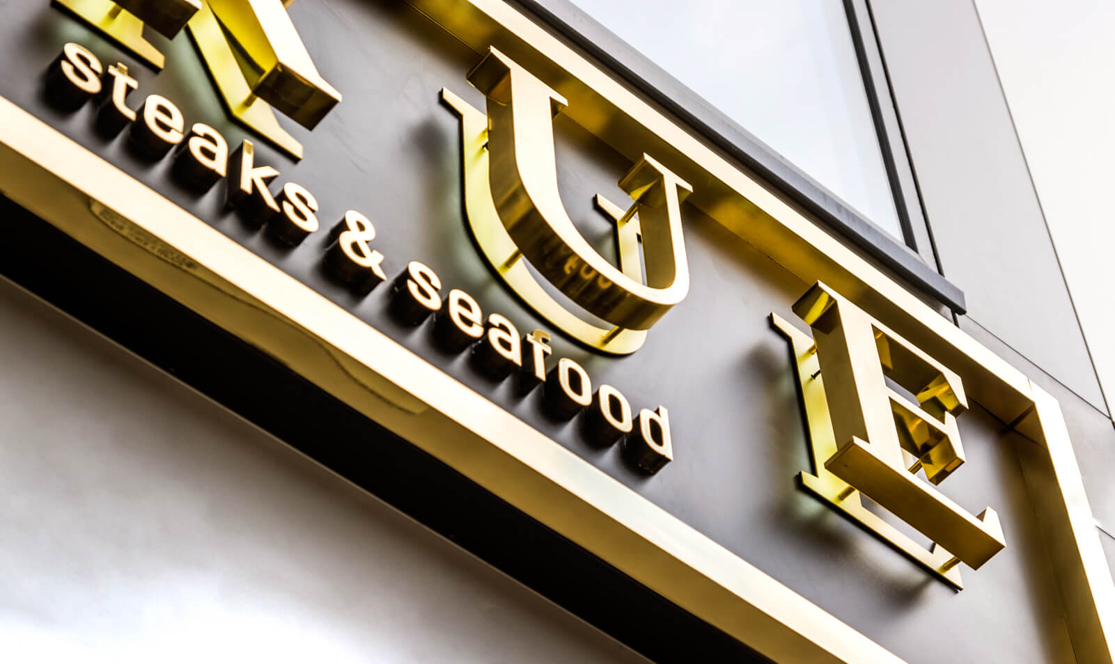 TRUE - True - external sign with golden letters made of stainless steel