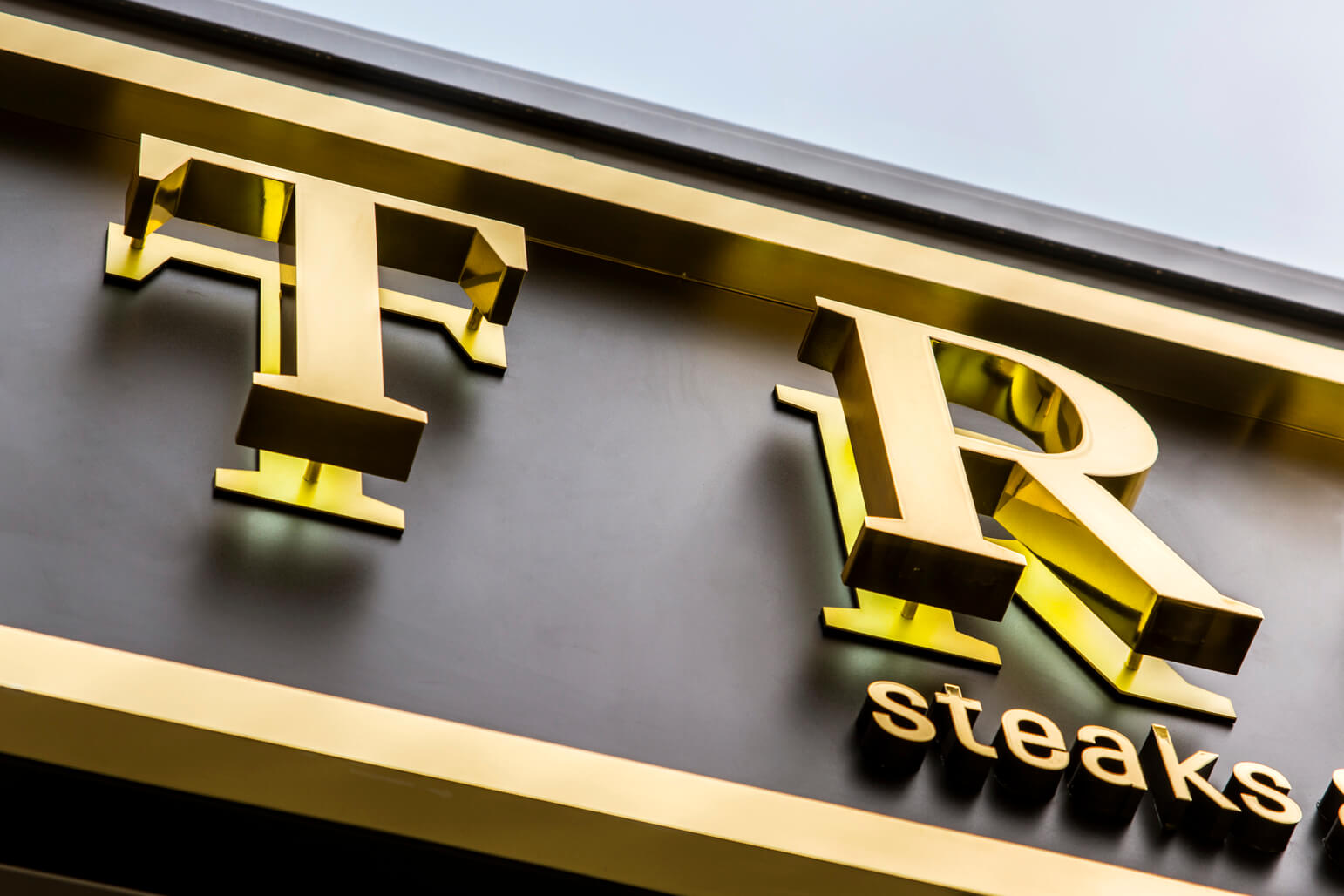 TRUE - True - external sign with golden letters made of stainless steel sheet