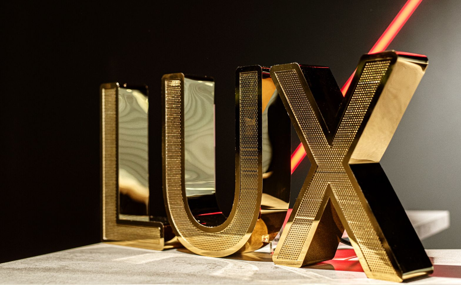 LUX litery z blachy nierdzewnej perforowanej - Litery LUX ze złotej połyskującej blachy nierdzewnej perforowanej w salonie Mercedesa