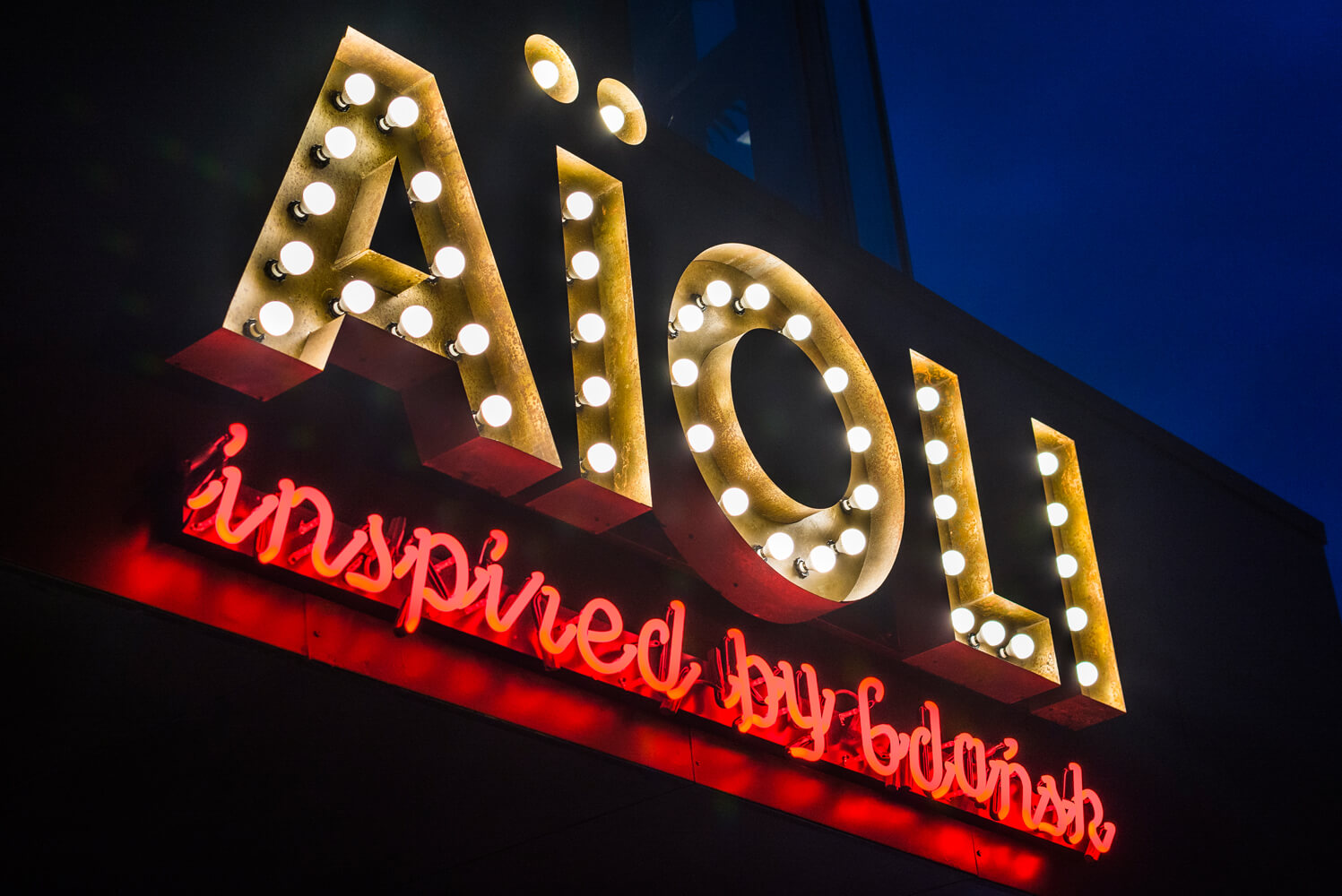 AIOLI - Aioli - szyld firmy zlożony z liter z żarówkami nad wejściem