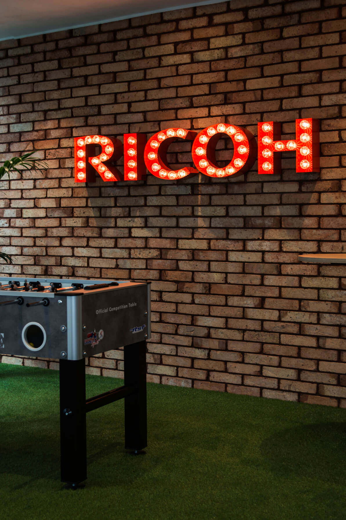 RICOH - RICOH - litery z żarówkami na ścianie ceglanej
