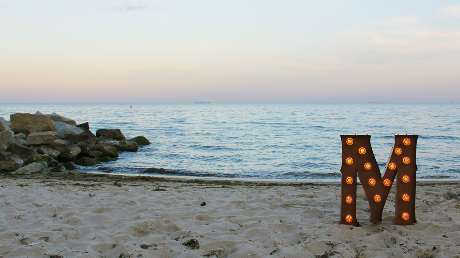 lettres avec ampoules - Lettrage spatial debout avec ampoules sur une plage