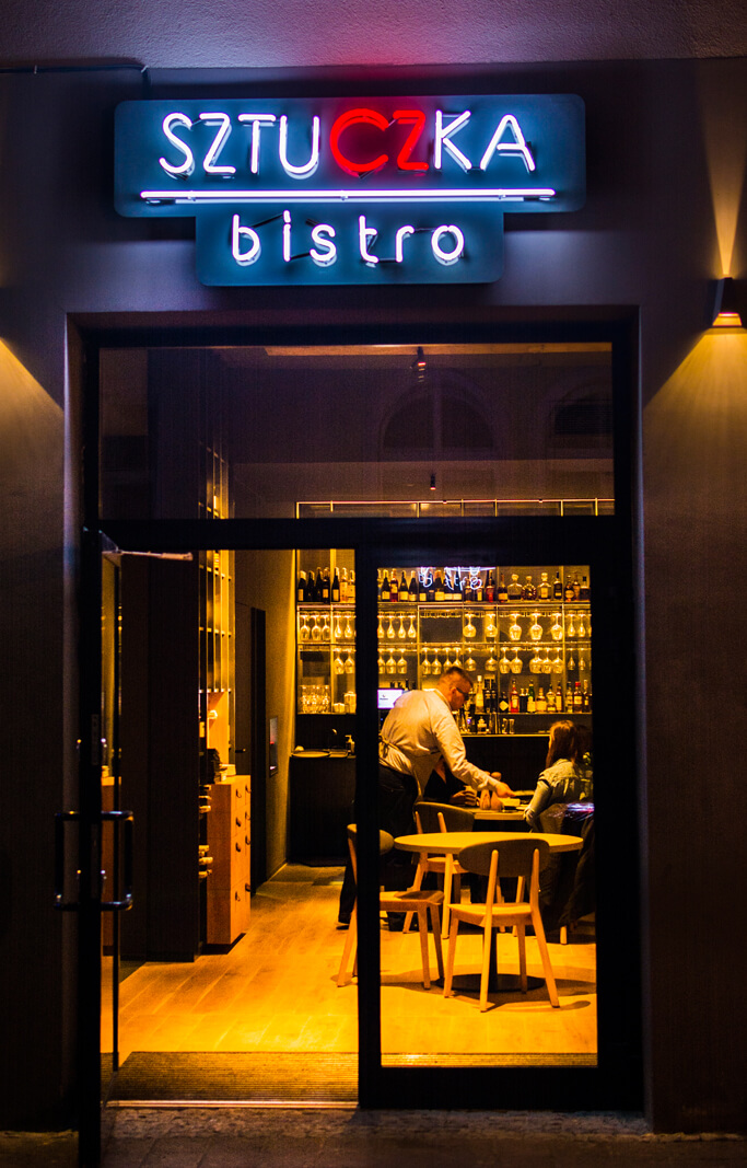 Trick Bistro - Sztuczka Bistro - enseigne au néon installée sur un panneau en plexiglas, placée au-dessus de l'entrée