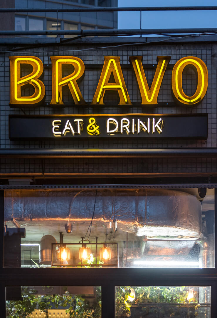 BRAVO - neon-bravo-eat-drink-neon-nad-wejsciem-do-restauracji-neon-na-kaflach-neon-na-scianie-z-kafli-neon-podswietlany-neon-wewnatrz-blachy-nierdzewnej-neon-na-zewnatrz-zolty-neon-warszawa-centralna