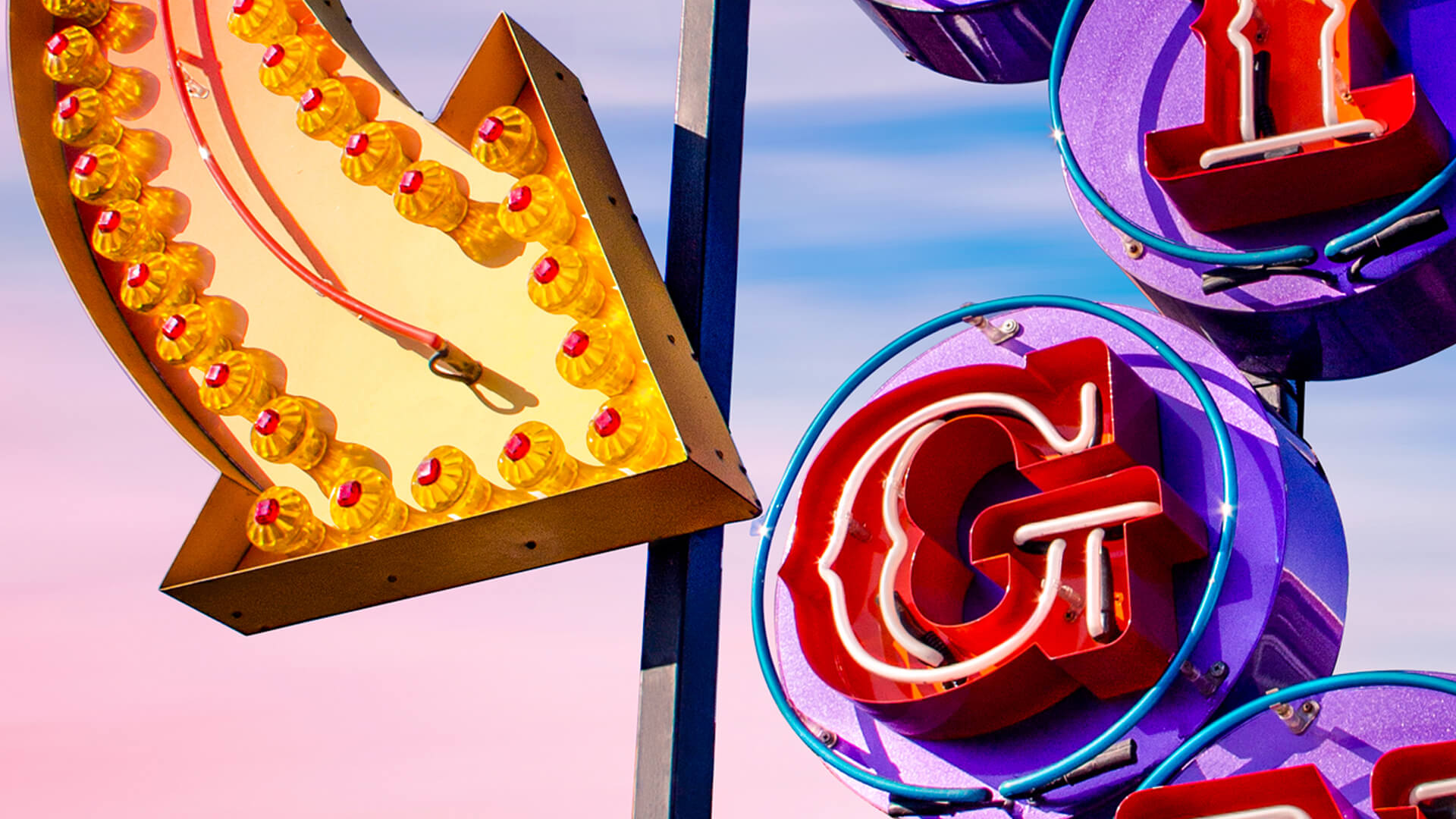 Neon Signs - Arrow illuminated by light bulbs, pointing to the letter G of Signs