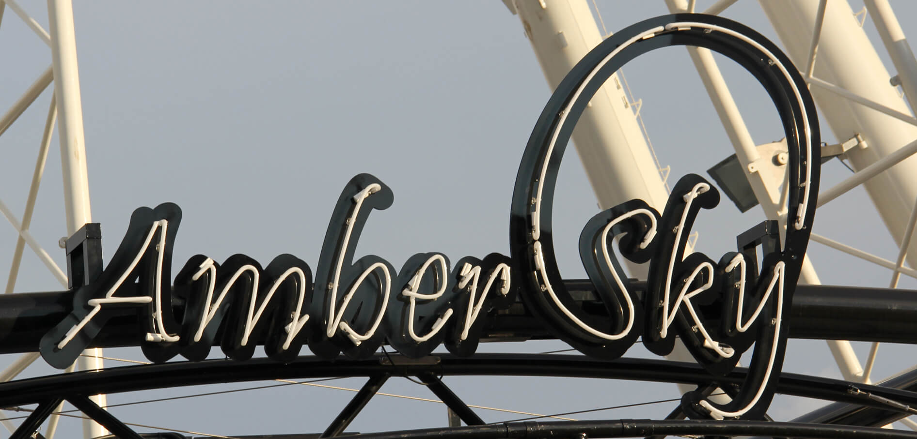 Bernsteinfarbener Himmel - Amber Sky - weißes Neonschild mit Firmenname auf dem Regal