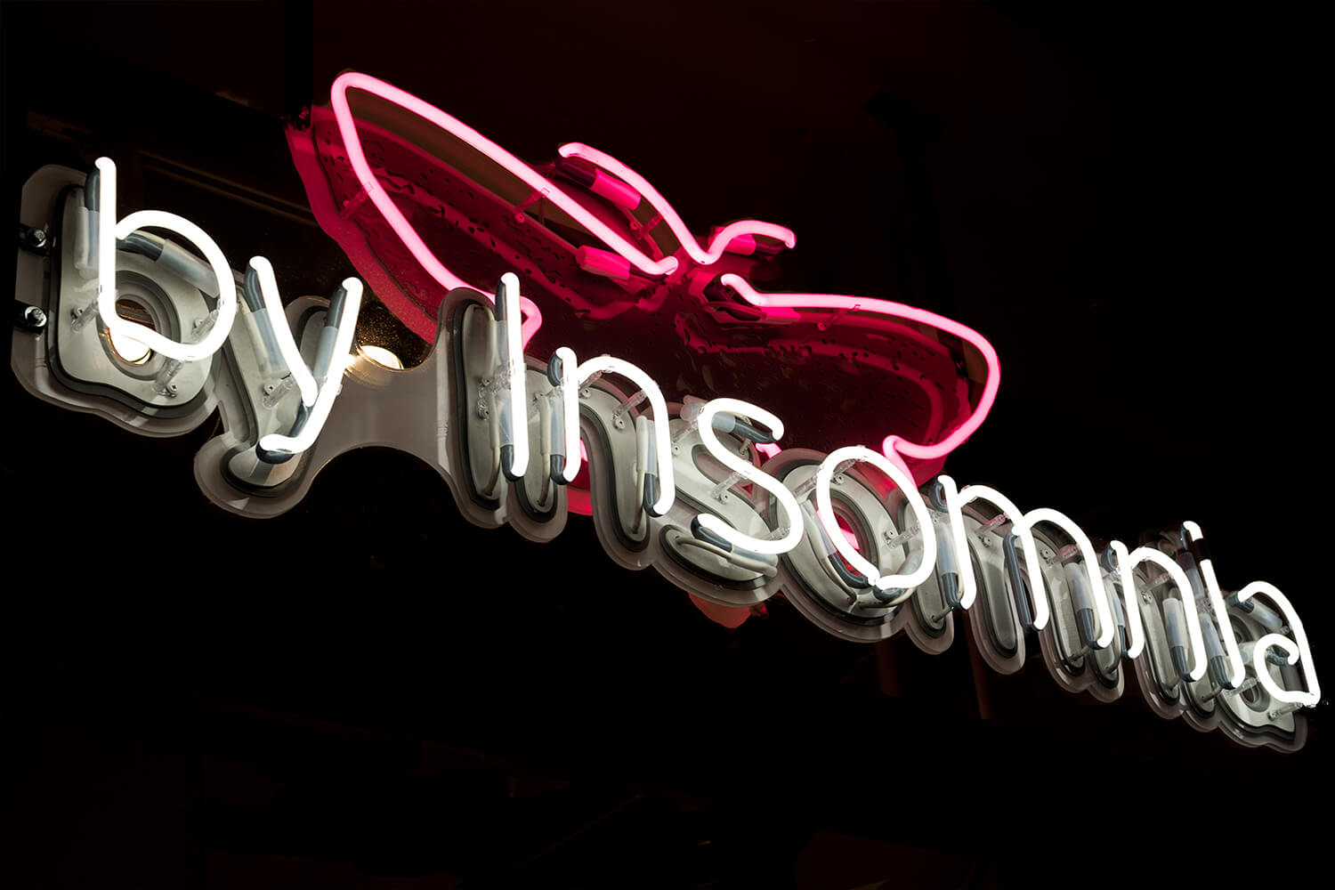 insomnie - By Insomnia - enseigne au néon portant le nom de la société, montée sur plexiglas, placée derrière la vitre.
