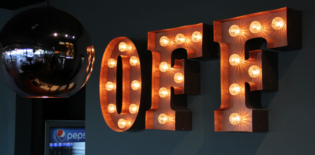 Buchstaben mit Glühbirnen ein aus - Mit Glühbirnen gefüllte Buchstaben an einer Wand im Inneren eines Gebäudes