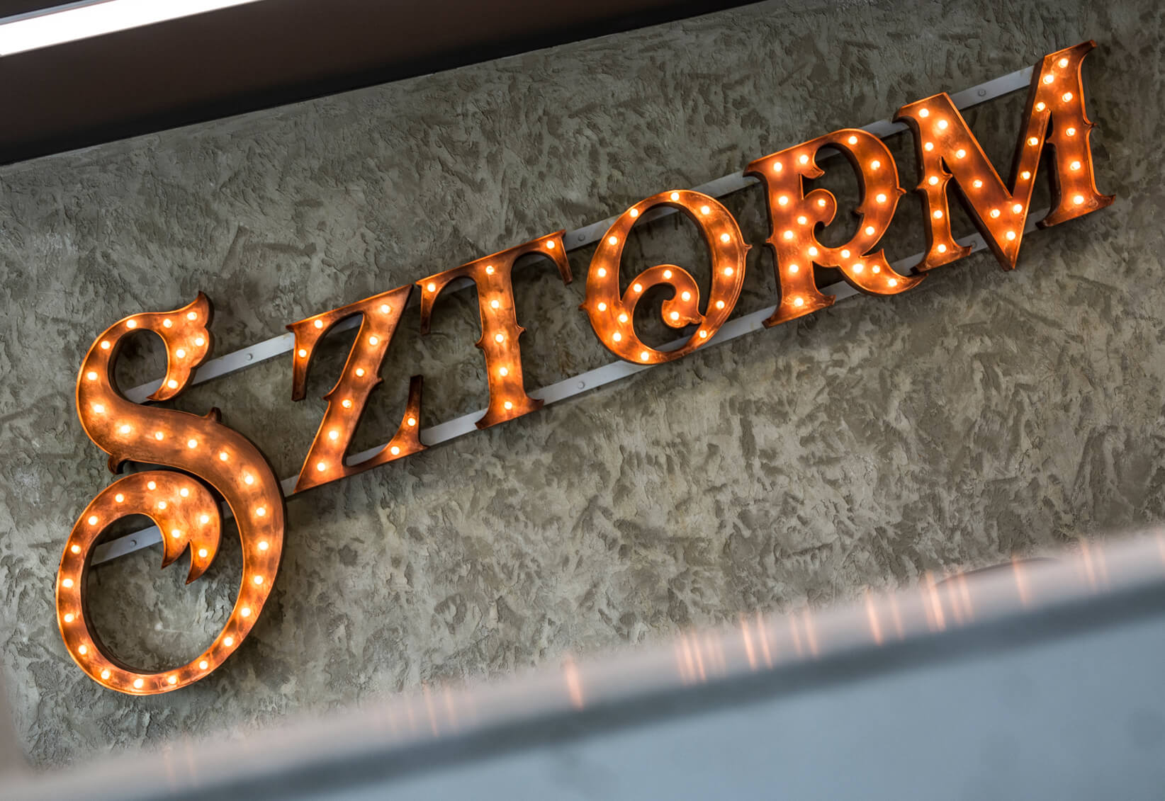 SZTORM - SZTORM - Buchstaben mit Glühbirnen auf einem Rahmen auf Beton