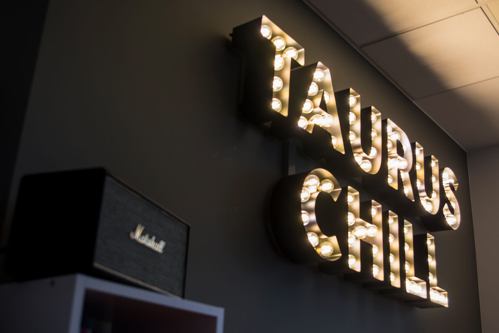 Taurus Chill - Taurus Chill - Buchstaben mit Glühbirnen an der Wand